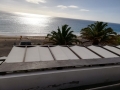 Fâșie romană economică albă de 2,1x5 m montată ca acoperiș de terasă cu vedere la mare și palmieri