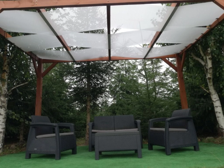 Weißes Sonnensegel für die Pergola montiert auf einer Holzpergola über Gartenmöbeln auf der Terrasse