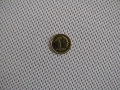 Moneda de 1 grosz sobre fondo de malla de ocultación para balcón blanca de tejido denso, mostrando la escala del material