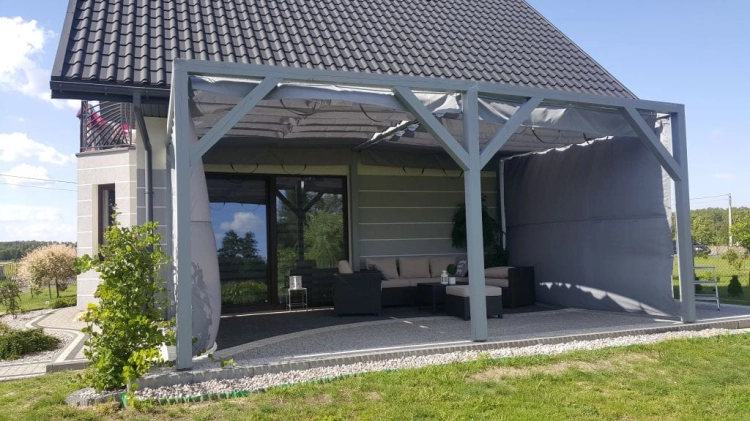 Light gray waterproof Roman patio blind on a 3x4 m wooden pergola with outdoor lounge furniture on a terrace