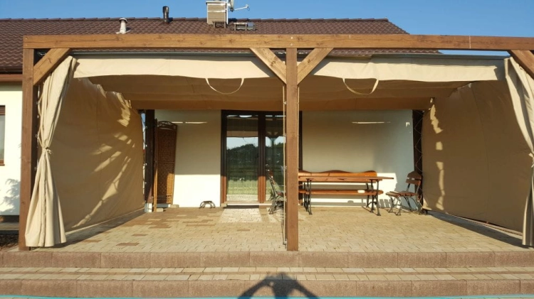 Premium beige waterproof roman blind installed on a wooden terrace pergola for sun protection