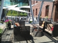 Wasserdichtes Premium Sonnensegel Dreieck über einer modernen Terrasse mit Rattanmöbeln und Pflanzen in Töpfen