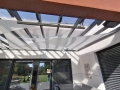 Wasserdichtes dreieckiges Premium-Sonnensegel unter einer Glasdach-Terrasse montiert
