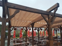 Wasserdichtes Premium Raffrollo für Terrassen 4x4 m, montiert an einer Holzpergola über Restauranttischen