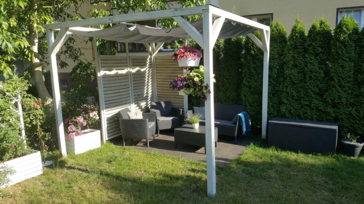 Wasserdichtes, ausziehbares Sonnensegel 2,5x5 m montiert an einer weißen Pergola über Gartenmöbel-Set