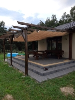 Wasserdichtes, ausziehbares Sonnensegel 3x3 m montiert an einer Holzpergola auf einer gepflasterten Terrasse