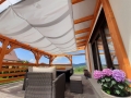 Weißes wasserdichtes Sonnensegel ausziehbar auf Holzkonstruktion über Terrasse mit Gartenmöbeln