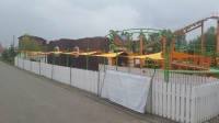Dreieckiges gelbes Premium Sonnensegel im Garten über einem Pfad in einem Freizeitpark montiert