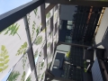 Wasserdichte Sonnenschutz-Pavillonbahn mit grünem Blattmotiv, montiert an einer Holzpergola-Konstruktion