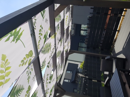 Waterdichte zonnebaan voor paviljoen met groen bladmotief, gemonteerd op houten pergola