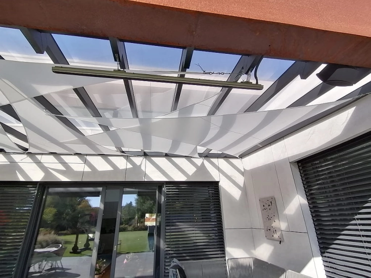 Triangle waterproof sun sail shade installed over a modern patio with glass roof and outdoor furniture.