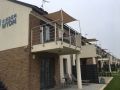Tan waterproof shade sail installed on a modern balcony railing for sun protection.