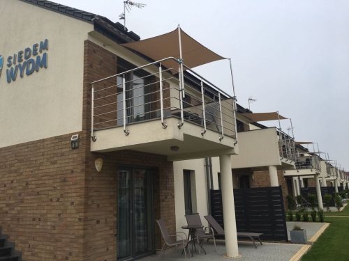 Waterdicht schaduwdoek op maat gemonteerd boven een modern terras en balkon