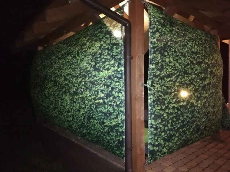 Tenda da giardino verde con stampa di foglie montata su un gazebo in legno come protezione dai vicini