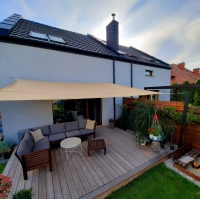 Béžová štvorcová slnečná clona 5x5 m z HDPE namontovaná nad terasou s záhradným nábytkom