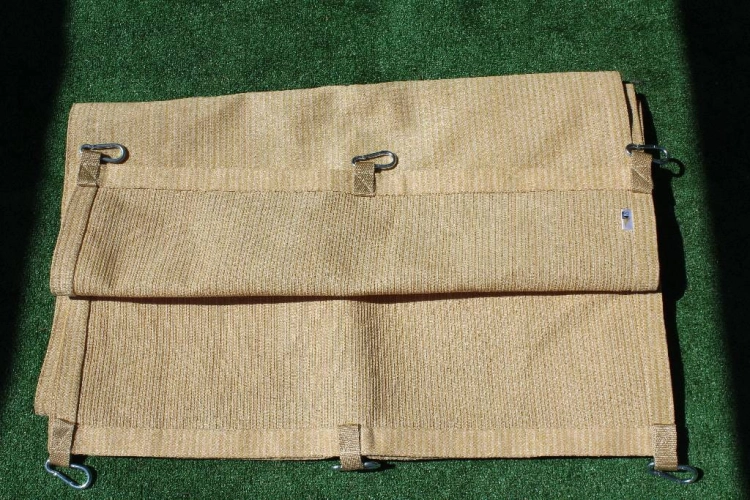 Beige HDPE sunshade privacy screen strip with metal mounting clips, laid out on a green surface outdoors.
