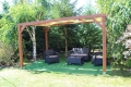 Gelbes HDPE-Sonnensegel für Pavillons, montiert an einer Holzpergola mit Gartenmöbeln auf dem Rasen