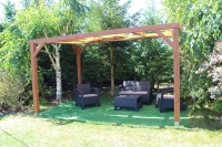 HDPE sun shade sail strip woven through a wooden garden pergola with outdoor wicker patio furniture on green turf