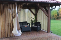 Tuingordijn met bamboescheuten print op een terras met tuinmeubelen en een hangstoel cocon