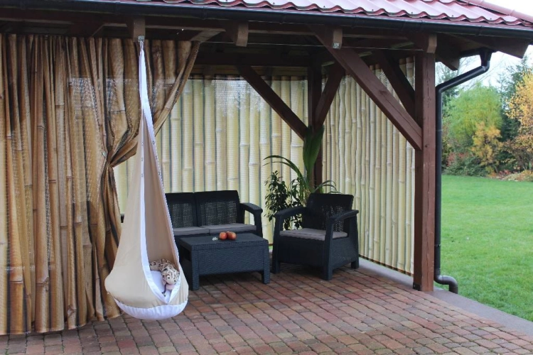 Tuingordijn met bamboescheuten print op een terras met tuinmeubelen en een hangstoel cocon