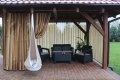 Rideau de jardin avec imprimé de tiges de bambou sur une terrasse avec meubles de jardin et fauteuil suspendu cocon