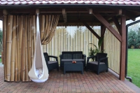 Outdoor curtains with a bamboo print hanging on a gazebo with patio furniture.