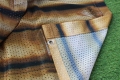 Close-up van een bedrukt tuingordijn, zichtbare netstructuur van het materiaal en metalen bevestigingsoog