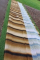 Tenda da giardino con stampa finto legno, stesa sull'erba accanto a un vialetto
