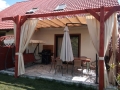 Cortinas de jardín premium a medida, instaladas en una pérgola de madera para terraza con muebles de jardín