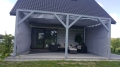 Cortina de terraza premium gris a medida, montada en un cenador de madera con muebles de jardín