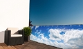 Balkonscherm op maat met print van blauwe lucht en wolken gemonteerd op het terrashekwerk