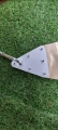 White triangular corner plate on a cream waterproof PVC sun sail with a metal carabiner against a green grass background