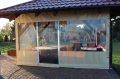 Custom clear PVC tarpaulin enclosure for a wooden terrace patio with a hot tub and lounge seating inside