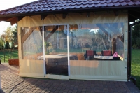 Custom clear PVC tarpaulin enclosure for a wooden terrace patio with a hot tub and lounge seating inside