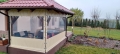 Transparente Terrassenplane mit beigem Rand, montiert an einer Holz-Pavillon-Konstruktion mit Möbeln und Whirlpool