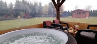 Transparent tarpaulin side wall for a terrace gazebo with a view of a bubbling hot tub and backyard garden