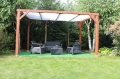 Weißes Sonnensegel nach Maß montiert an einer Holzpergola im Garten mit Loungemöbeln