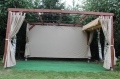 Custom waterproof garden curtains and side panels on a wooden pergola with artificial grass flooring.