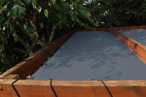 Graues HDPE Sonnensegel nach Maß, montiert an einer Holzkonstruktion mit elastischen Seilen