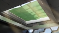 Store pare-soleil vert sur mesure installé sous le lanterneau pour ombrager l'intérieur du bâtiment