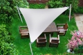 Custom-sized white outdoor sun shade sail over a wooden garden dining set in a lush backyard.