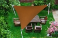 Custom-made brown waterproof PVC sun shade sail triangle covering a wooden patio table and chairs in a green garden