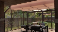 Custom retractable horizontal awning for a sunroom covering a modern patio dining set with a garden view.