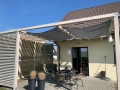 Graues Sonnensegel wasserdicht ausziehbar 3x3 m montiert auf einer Holzpergola über der Terrasse mit Loungemöbeln