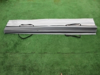 Tenda a pacchetto grigia impermeabile per terrazza in PVC con supporti neri, piegata su fondo verde