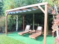 Wasserdichtes PVC-Raffrollo für Terrassen nach Maß, montiert an einer Holzpergola mit Gartenliegen