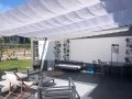 Vela ombreggiante scorrevole bianca impermeabile montata su una terrazza con mobili da giardino moderni su misura