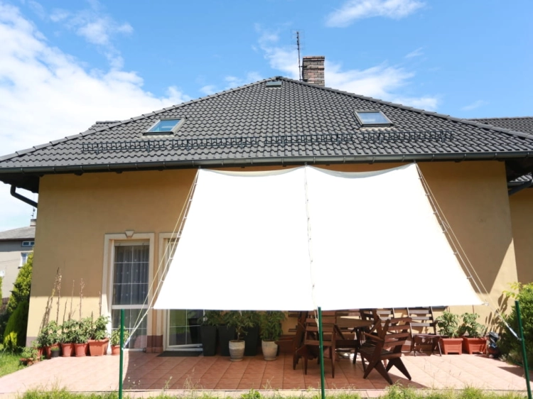 Large waterproof white retractable sun shade sail over a garden patio with table and chairs.