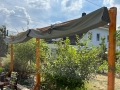 Graues Sonnensegel wasserdicht ausziehbar 3x3 m montiert an einer Holzpergola im Garten