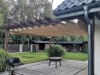 Beige 3x4 m waterproof retractable roman blind shade installed under a wooden pergola on a garden patio